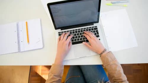 Une personne tapant sur son ordinateur portable assise à son bureau